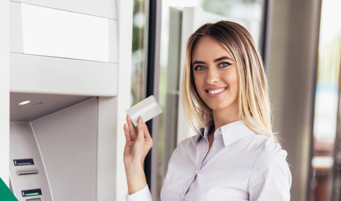 kobieta stojąca przed bankomatem z kartą