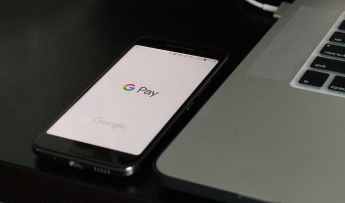 telefon leżący obok laptopa z logo G Pay na ekranie