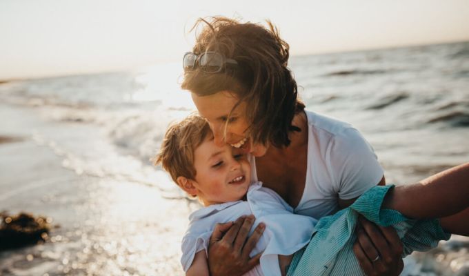 kobieta trzymająca chłopca na rękach na plaży