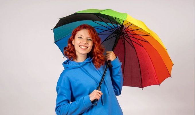 kobieta w niebieskiej bluzie pod kolorowym parasolem